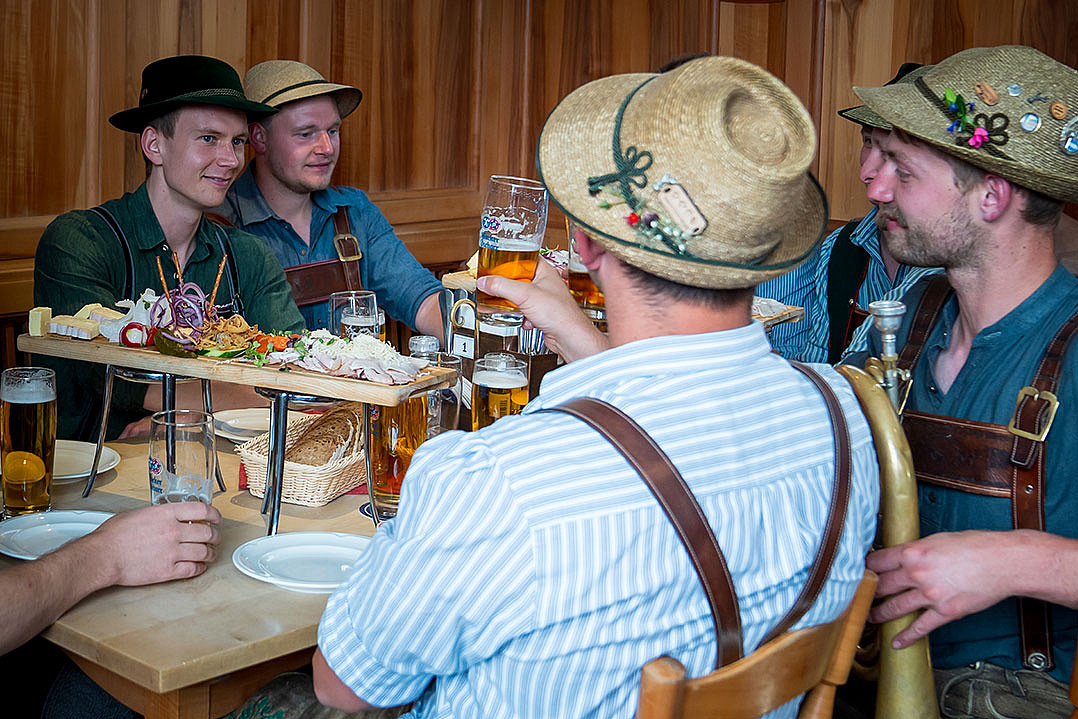 Männergruppe teilt sich eine Brotzeitplatte und trinkt Bier im Donsil Wirtshaus in München